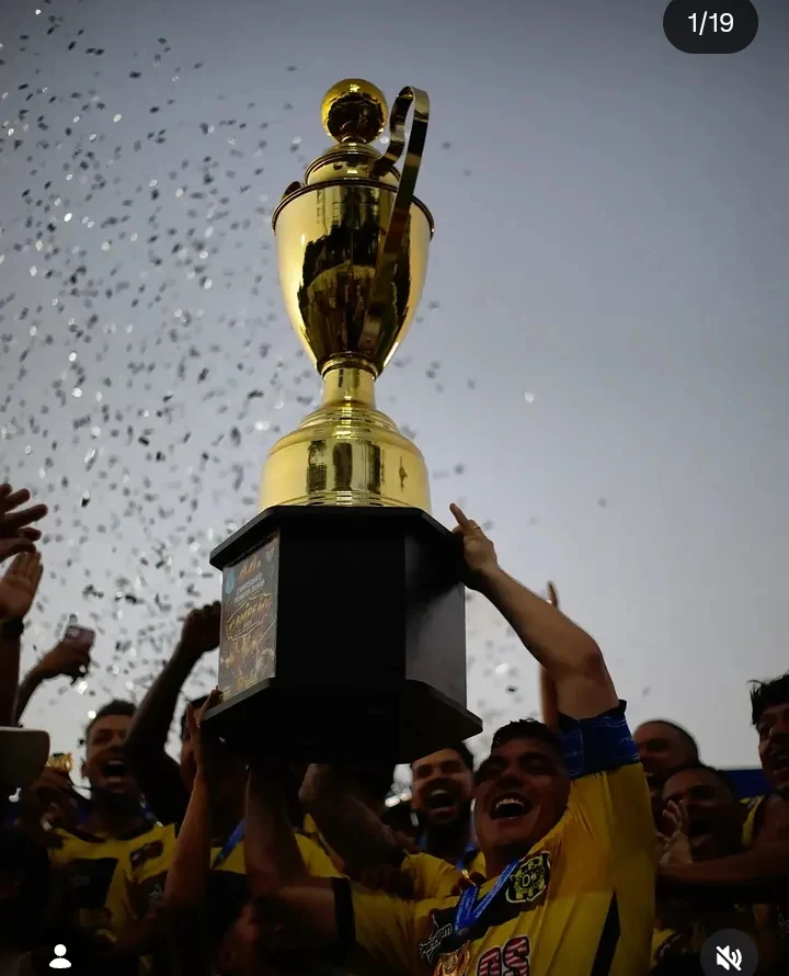 Taça de campeão levantada por atletas